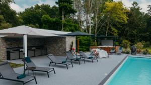 una piscina con sillas y sombrillas junto a una mesa y una piscina en LA MAISON CACHEE-BA, en La Teste-de-Buch