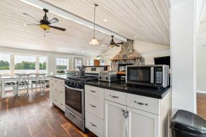 a kitchen with white cabinets and a stove top oven at Lakefront Gladwin Vacation Rental with Deck and Dock! in Gladwin