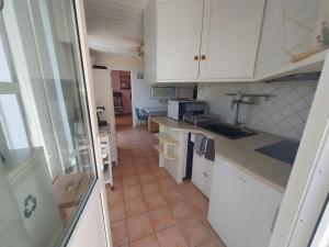 a kitchen with white cabinets and a tile floor at ALBASUD - Appartement meublé avec terrasse - Salses le Chateau 66 in Salses-le-Chateau