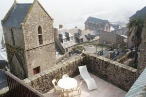 um edifício com uma mesa e cadeiras numa varanda em La Vieille Auberge em Monte de Saint Michel