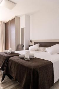 Dos camas en una habitación de hotel con toallas. en Mesón Hostal La Cabaña, en Medellín