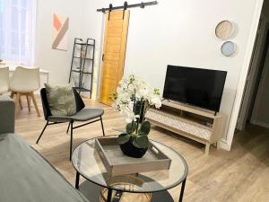 a living room with a tv and a vase of flowers at Arina & Julien Dieppe in Dieppe