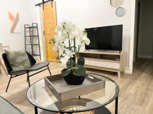 a living room with a glass table with a vase of flowers at Arina & Julien Dieppe in Dieppe