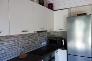 a kitchen with white cabinets and a stainless steel refrigerator at Holiday home near sea beach & pine forest in Riga