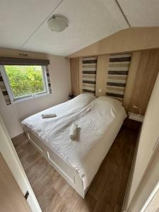 ein großes weißes Bett in einem Zimmer mit Fenster in der Unterkunft Chalet De Bult 4 pers in De Bult