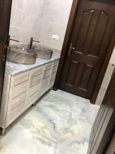 baño con 2 lavabos y puerta de madera en The Pine Tree Chalet, en Jerash