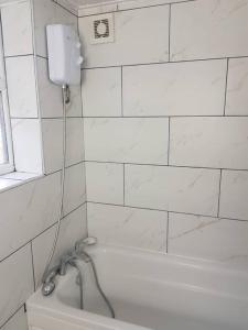 a white tiled bathroom with a bath tub and a window at Kunda House Parkhill in Birmingham