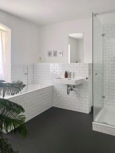 a white bathroom with a tub and a sink at Zehuus mit Domblick und Dachterrasse in Cologne