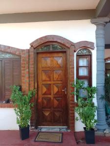 una puerta de madera en una casa con dos macetas en Flor de Lis en Puerto Iguazú