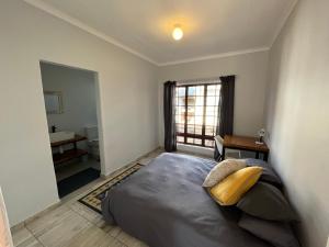 ein Schlafzimmer mit einem Bett und ein Bad mit einem Fenster in der Unterkunft Casa Bravo - Cozy Traveller in Pretoria