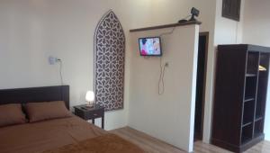 ein Schlafzimmer mit einem Bett und einem TV an der Wand in der Unterkunft Samawa Homestay syariah Batu in Tlekung