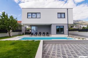 ein weißes Haus mit einem Swimmingpool davor in der Unterkunft Kastel One in Kaštela