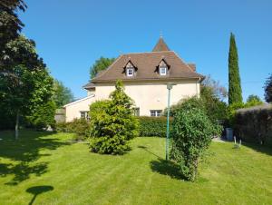 une maison dans une cour avec deux arbres dans l'herbe dans l'établissement Gîtes "La Sérénité Marivaloise", à Lacapelle-Marival