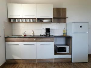 a kitchen with white cabinets and a white refrigerator at Apartmani Zen in Sumartin