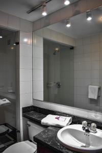 La salle de bains est pourvue d'un lavabo, d'un miroir et de toilettes. dans l'établissement Cora 96 Street Apartments, à Bogotá