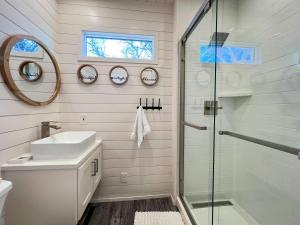 a bathroom with a shower and a sink and a mirror at NEW The Flagship 2 Story Container Home in Waco