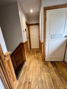an empty hallway with a white door and wooden floors at Cosy Single Room for ONE person in Bromley
