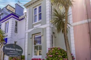 a white building with a palm tree in front of it at Sandway House in Torquay