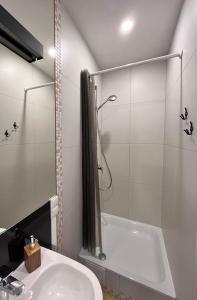 een badkamer met een wit bad en een wastafel bij Stilingi šaulio skulptūros apartamentai in Druskininkai