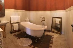 Residence Spillenberg Bridal Suite - Svadobna cesta في ليفوتشا: حوض استحمام في الحمام مع مرآة