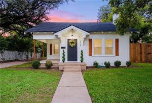 una pequeña casa blanca con una corona en la puerta en NEW-Ethel Rose Cottage-5 min to Magnolia Silos, en Waco