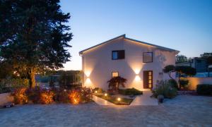 a large white house with lights in a yard at Caprice in Milohnići
