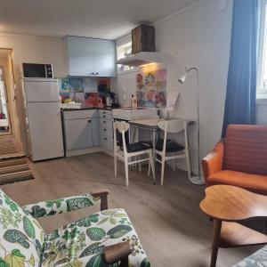 a living room with a kitchen and a table with chairs at Liten leilighet i Berlevåg in Berlevåg