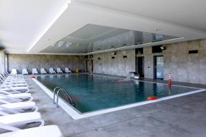 ein großer Pool mit weißen Stühlen in einem Gebäude in der Unterkunft Apartament z Mewami - Dziwnów Bridge Apartaments & Spa in Dziwnów