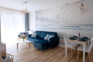 ein Wohnzimmer mit einem blauen Sofa und einem Tisch in der Unterkunft Apartament z Mewami - Dziwnów Bridge Apartaments & Spa in Dziwnów