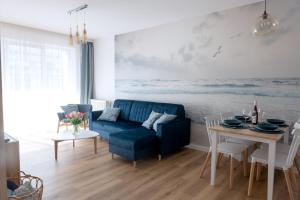 a living room with a blue couch and a table at Apartament z Mewami - Dziwnów Bridge Apartaments & Spa in Dziwnów