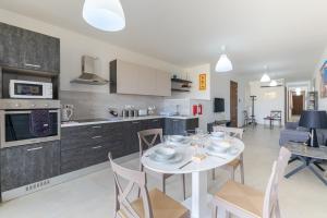 Il comprend une cuisine et une salle à manger avec une table et des chaises blanches. dans l'établissement Brand New Apartment 3Bdr 2 Bth H12, à San Pawl il-Baħar