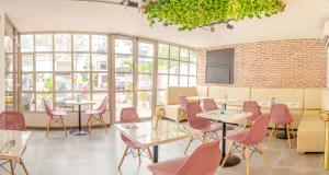 卡塔赫纳Casa Franco Hotel的餐厅设有粉红色的椅子和桌子以及窗户。
