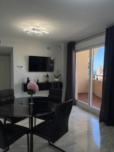 a dining room with a glass table and a television at Luxury apartment Benalmadena First line in Benalmádena