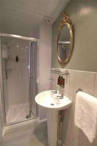 a bathroom with a sink and a shower and a mirror at The Snowdonia Apartments in Llandudno