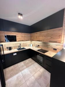 a large kitchen with black cabinets and a sink at Comfy Apartment Kłodzko in Kłodzko