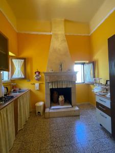 cocina con chimenea y paredes amarillas en B&B Al Castello, en Sammichele di Bari