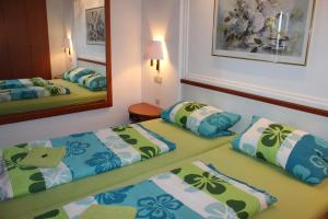 two beds in a room with a mirror at Ristorante Pizzeria Pension Taormina in Roßhaupten