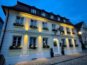 ein weißes Gebäude mit Fenstern und Blumenbeeten in der Unterkunft Hotel Zum Lamm in Ansbach