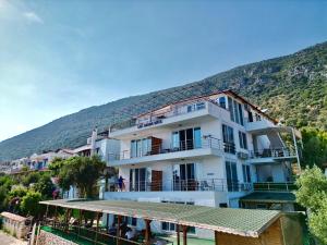 a large white building with a mountain in the background at Just Dream Suites in Kaş