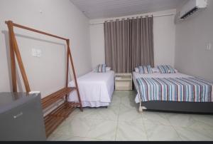 a hotel room with two beds and a window at Canoa Hospedagem in Barra Grande