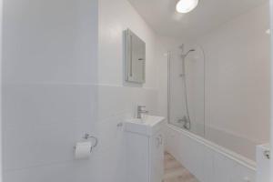 een witte badkamer met een wastafel en een douche bij Westward House - Norfolk Cottage Agency in Sheringham
