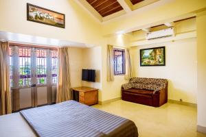 um quarto com uma cama, uma cadeira e uma janela em 'Golden Oceans' 3 bhk beach view villa em Benaulim