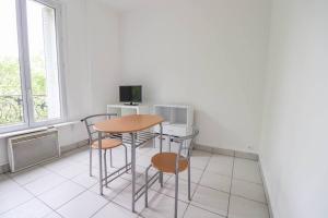 eine Küche mit einem Tisch und Stühlen sowie einem TV in der Unterkunft Montrouge 1 Bedroom Flat 30m2 - (2 pièces) in Montrouge