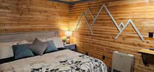 um quarto com paredes de madeira, uma cama e uma secretária em The Whispering Elms Motel em Baker