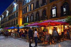 eine Gruppe von Menschen, die an Tischen unter Sonnenschirmen sitzen in der Unterkunft 4 Bedroom House in City Centre with Your Own Private Roof Terrace in Málaga