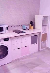 eine weiße Küche mit einer Mikrowelle und einem Herd in der Unterkunft 4 Bedroom House in City Centre with Your Own Private Roof Terrace in Málaga