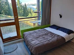 un lit dans une chambre avec une grande fenêtre dans l'établissement Arc 1800 - Studio 5p - Réservations du Samedi au Samedi uniquement, à Arc 1800