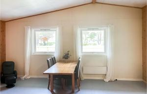 a dining room with a table and two windows at Amazing Home In Dovre With House A Panoramic View in Dovre