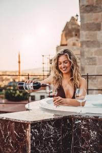 a woman is pouring a glass of wine at Secret Hill Cave Suites in Göreme