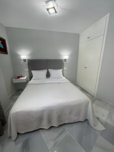 a white bedroom with a white bed and a white cabinet at Luxury apartment Benalmadena First line in Benalmádena